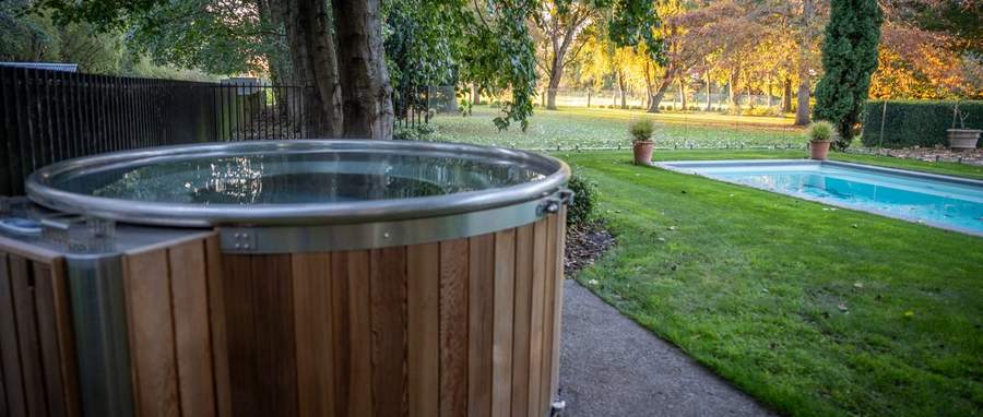 Cedar Tubby hot tub under old trees beside a pool at a French country homestead