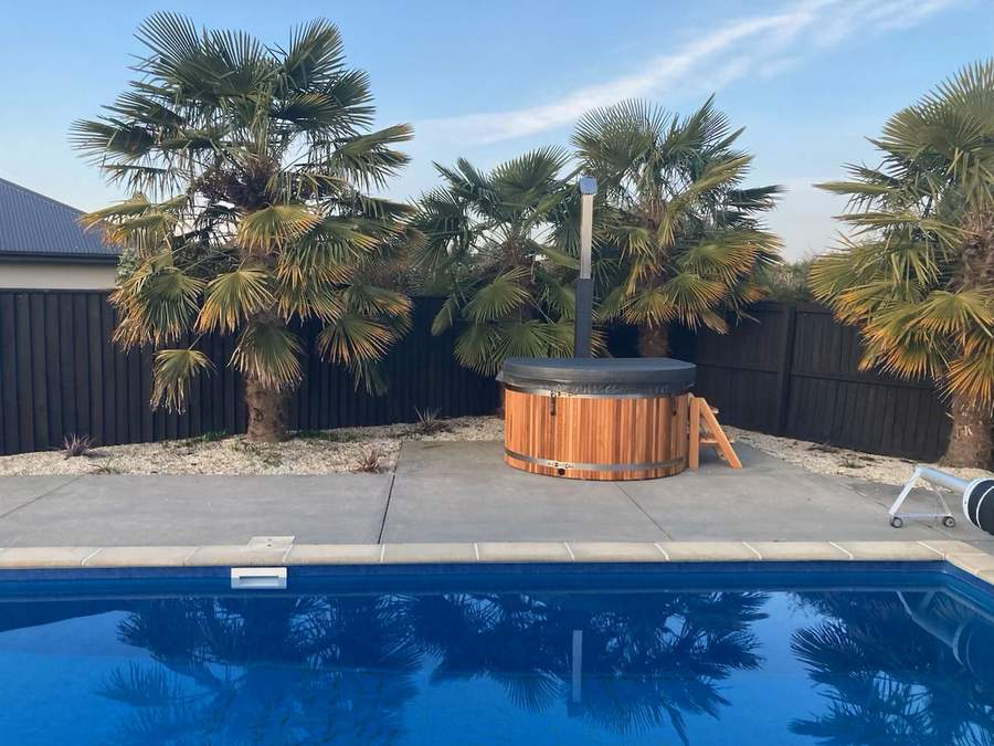 Tubby hot tub beside a swimming pool and palms in Prebbleton